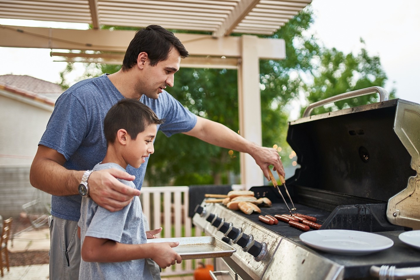 father and son cooking meat at a BBQ
