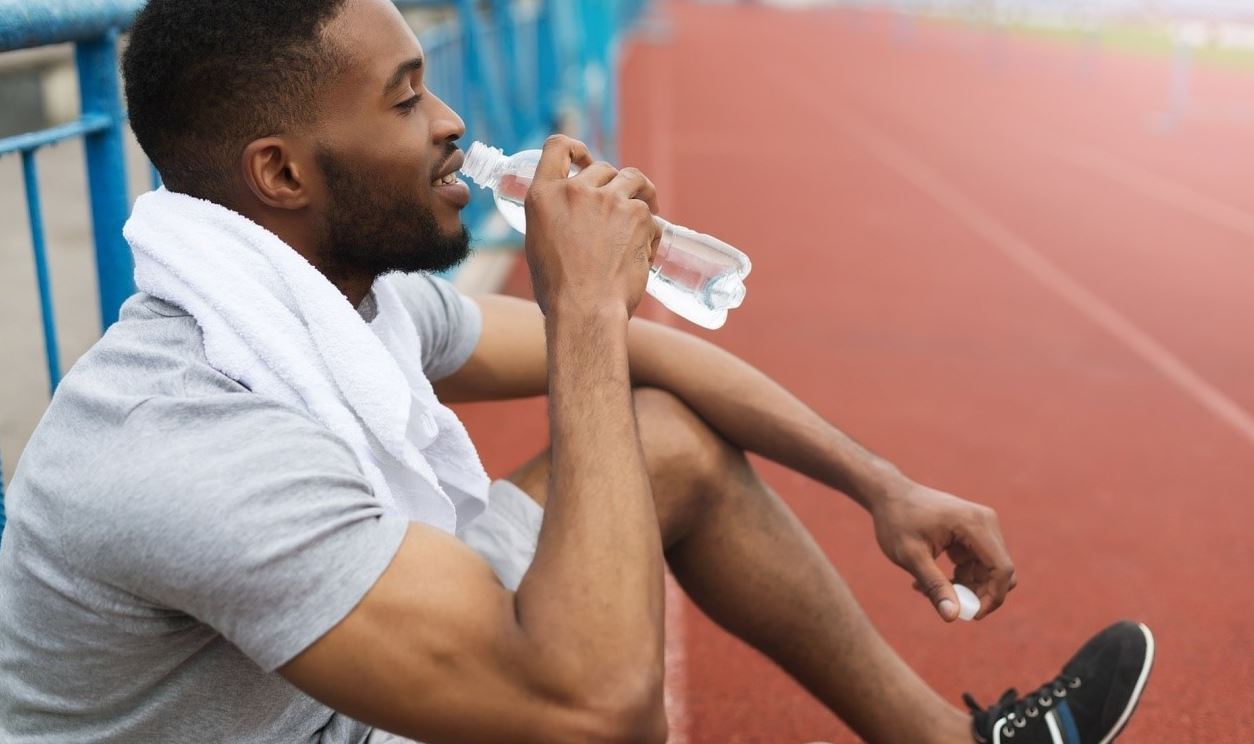 man on running track drinking functional bevearage