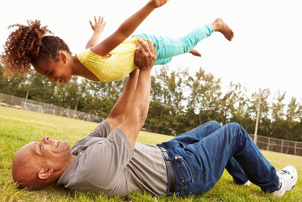 Man lifting child up in the air in a field
