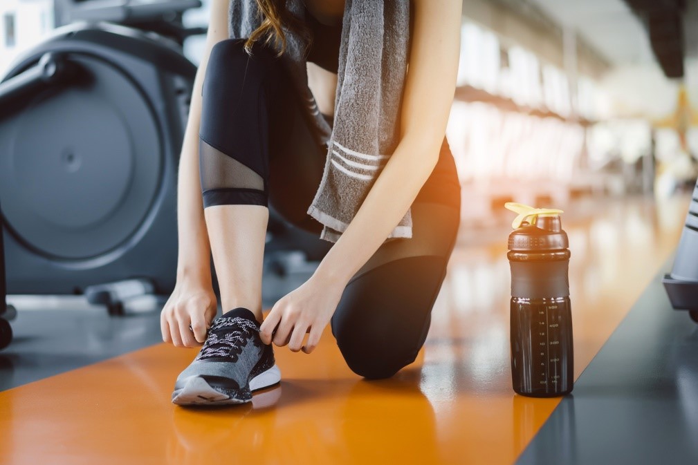 woman tying her shoe at the gym