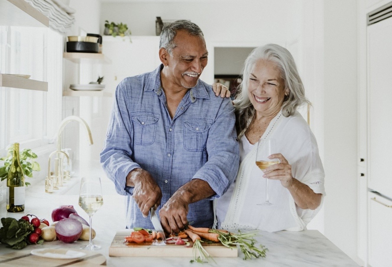 Senior couple in kitchen chopping veggies