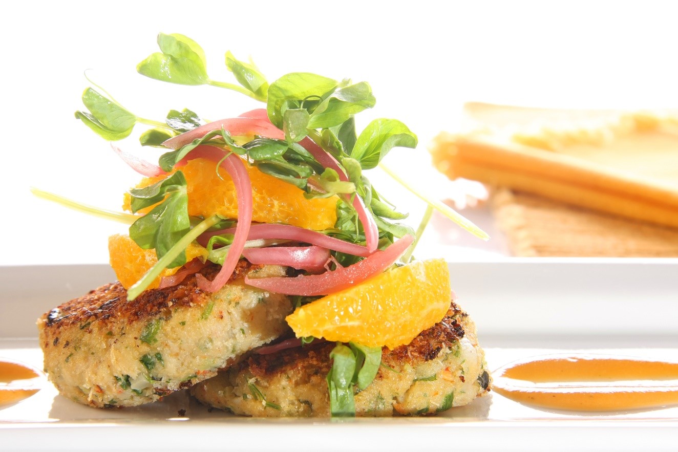 two meatless meat cakes on plate topped with veggies