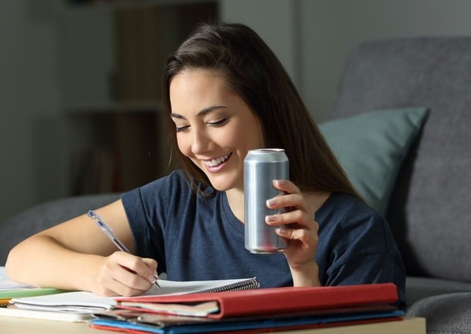 woman writing in notebook drinking beverage