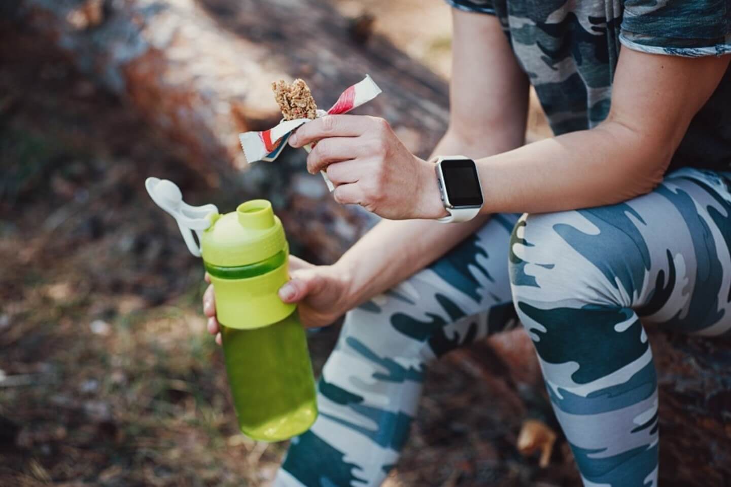 woman holding a bar and water bottle