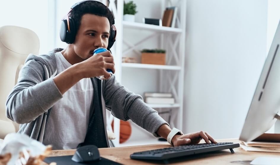 man drinking a drink while looking at computer