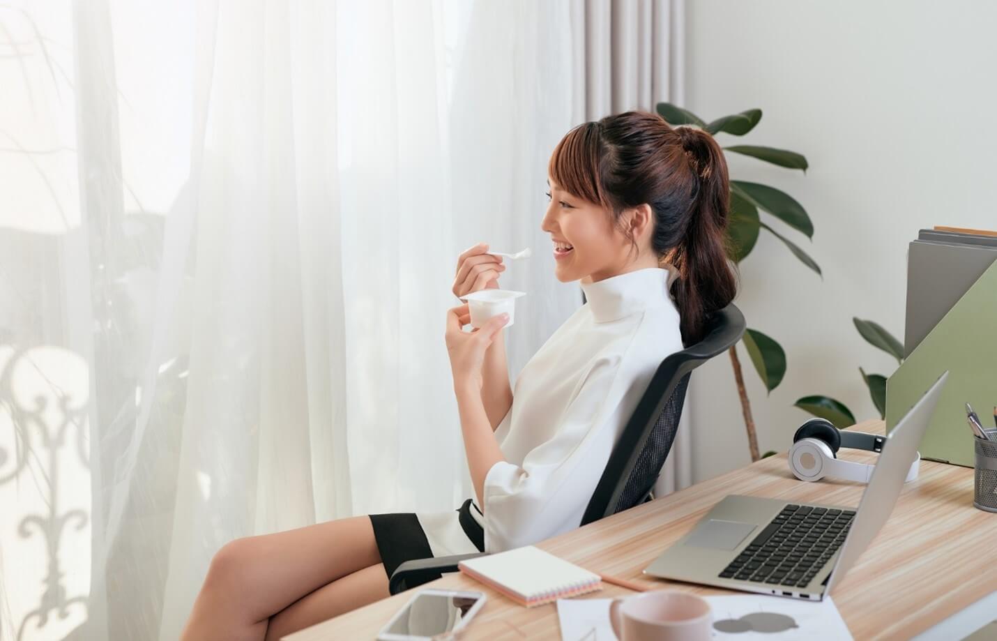 woman eating yogurt at desk