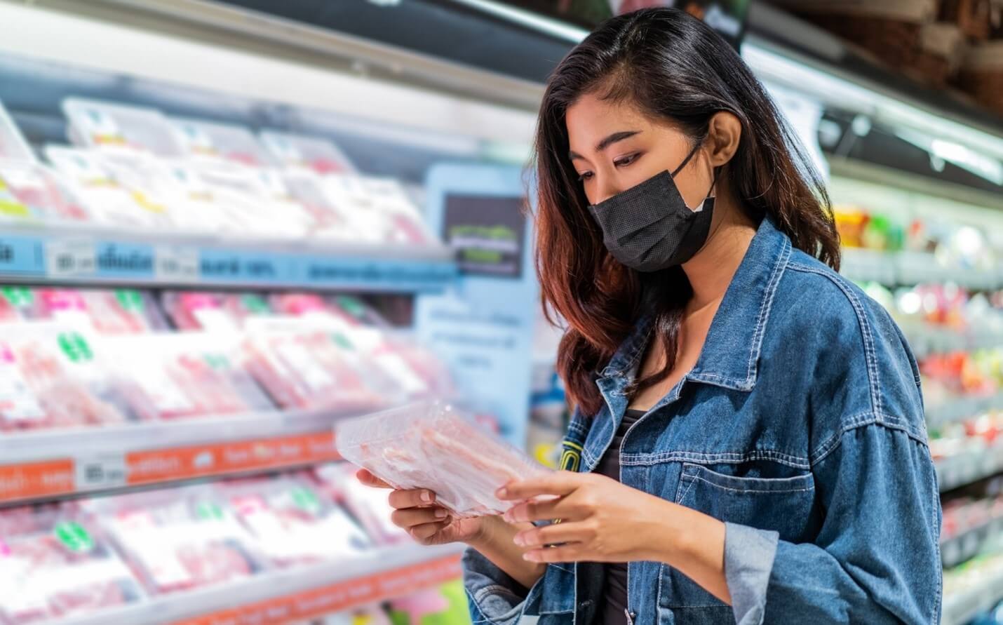 woman looking at meat with mask