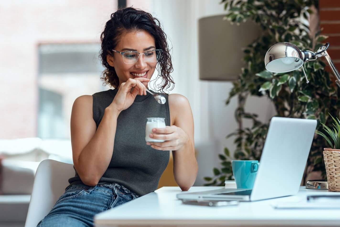 woman eating breakfast in front of laptop