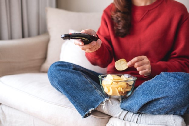 woman eating chips on couch