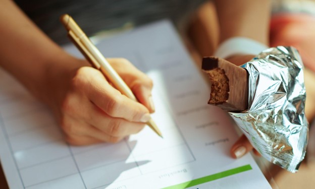 person eating bar while writing on paper