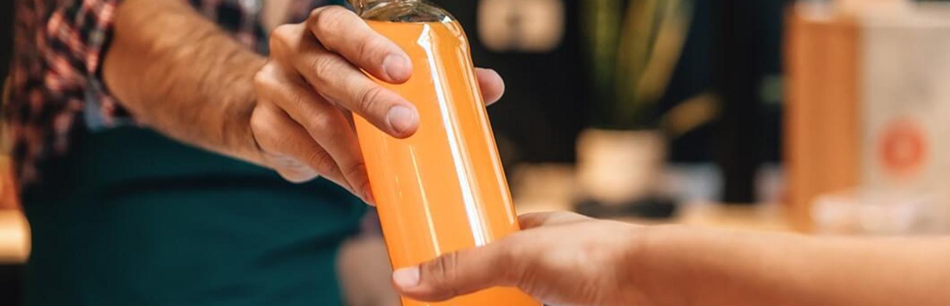 cashier handing customer bottle of juice