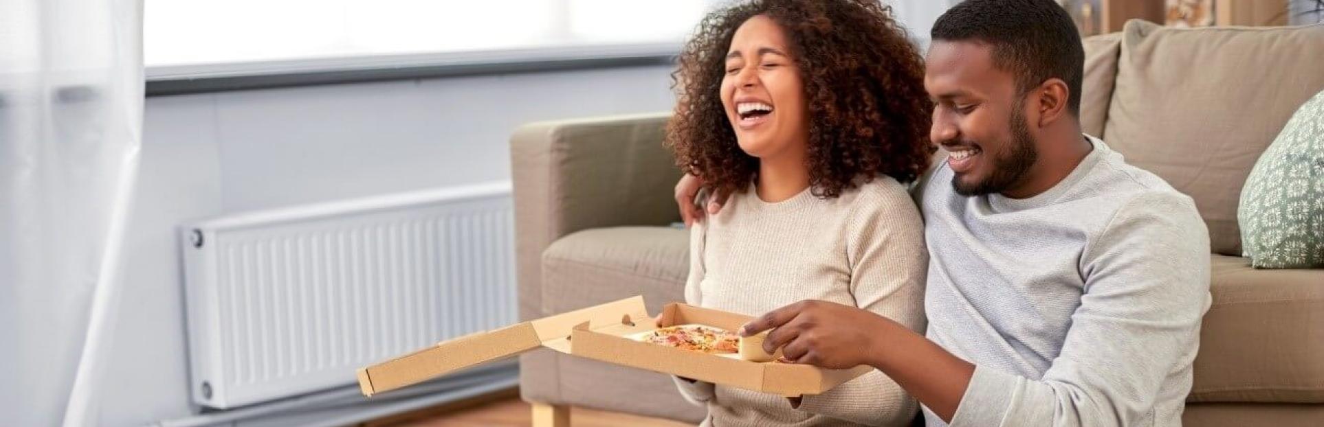 man and woman eating takeout pizza