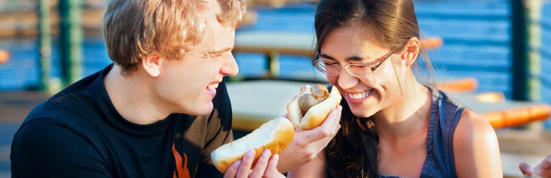 two people eating hot dogs