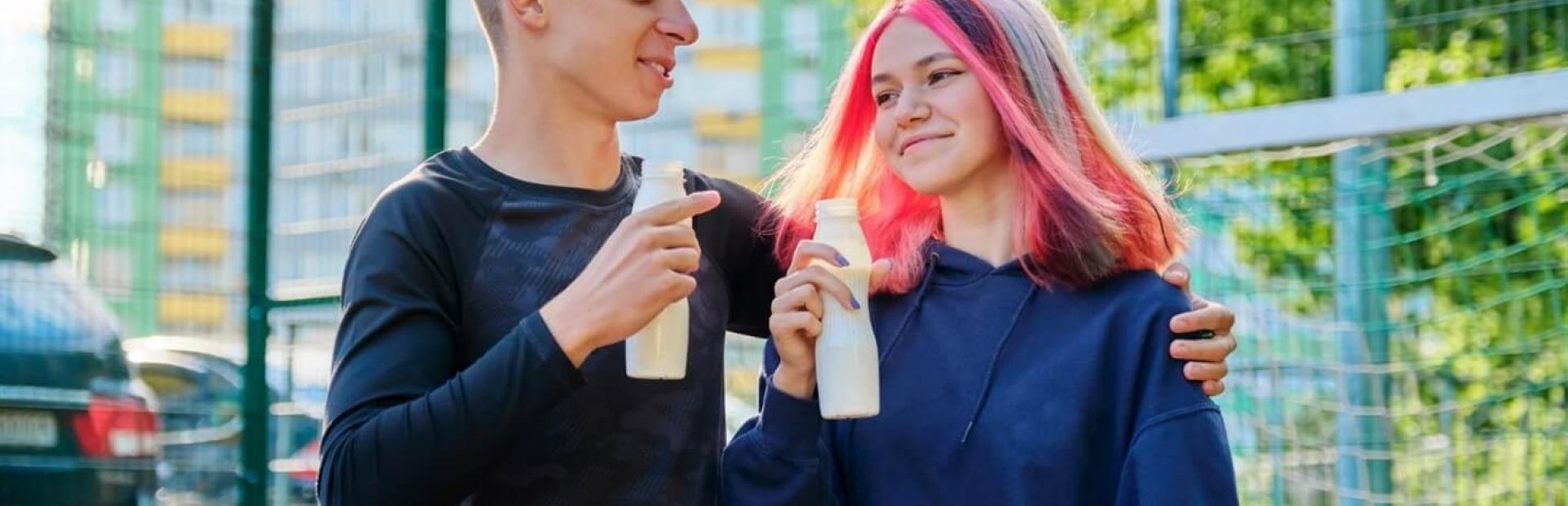 two teenagers walking and holding beverage