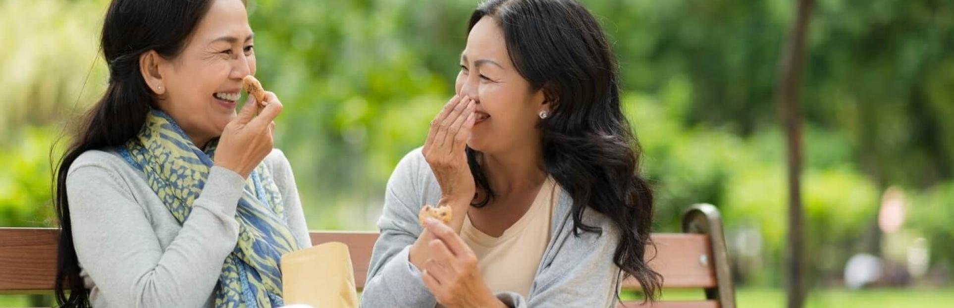 two women laughing on a bench