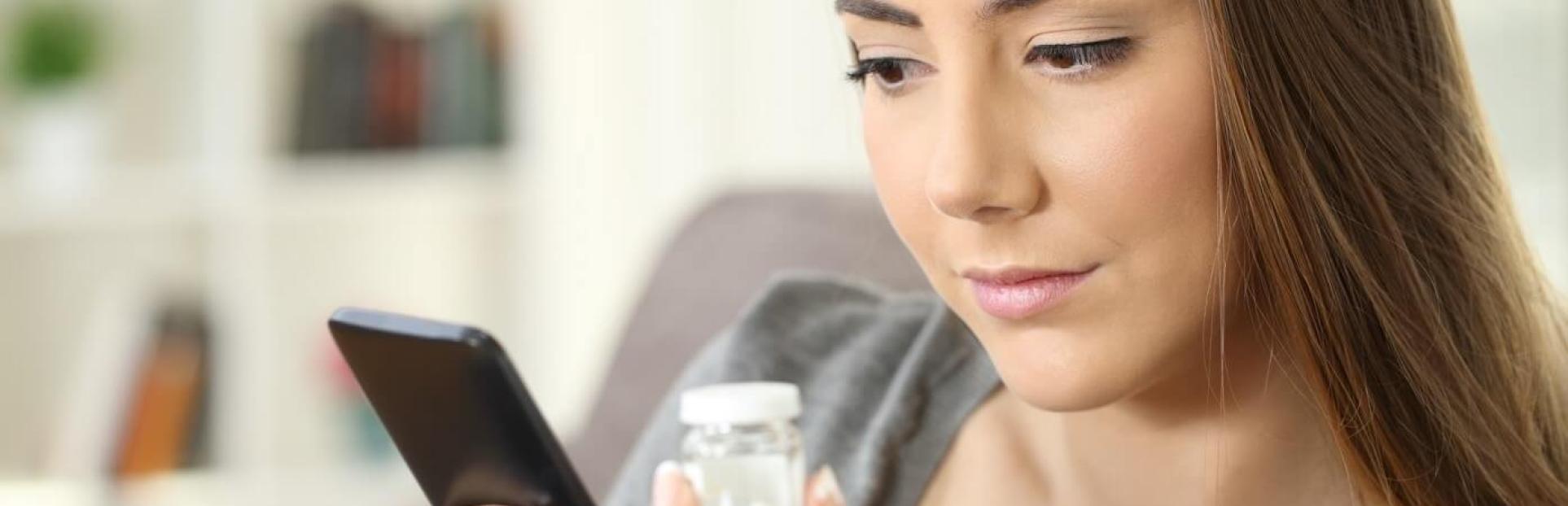 woman holding phone and supplements