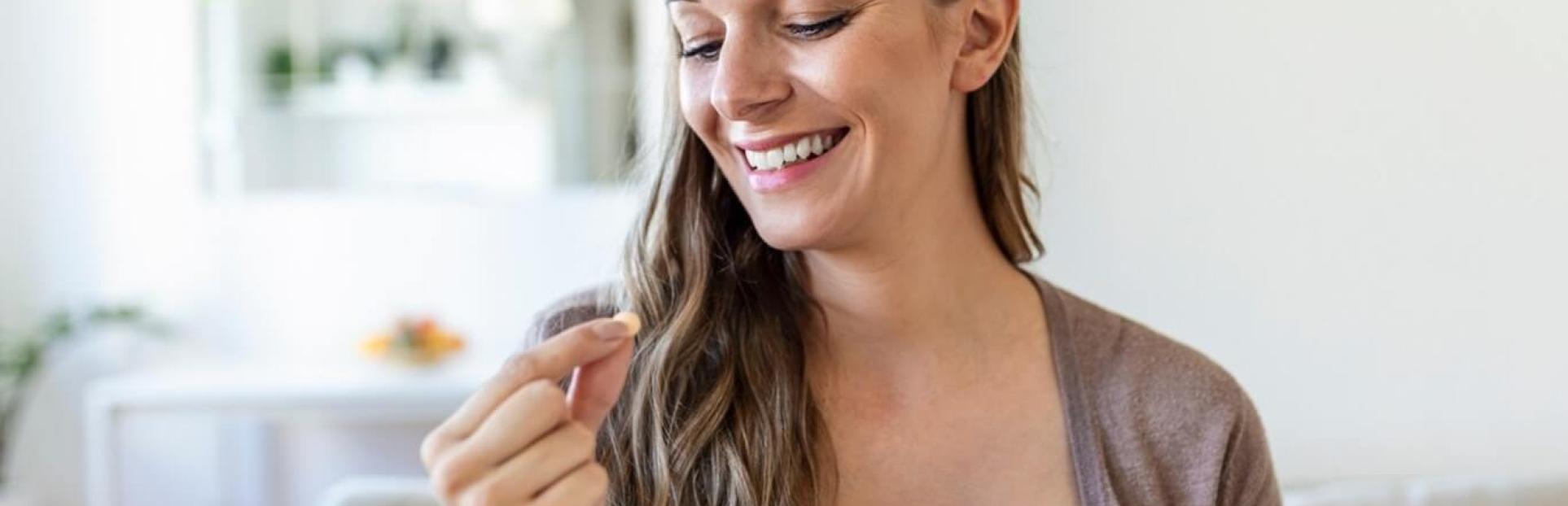 woman holding a supplement and water
