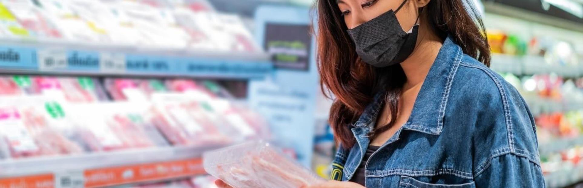 woman looking at meat in grocery store