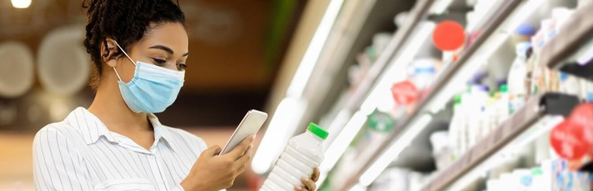 woman looking at phone and milk in store