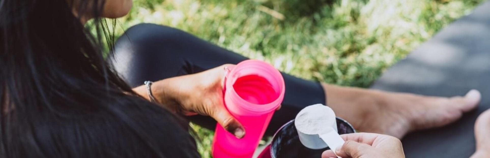 Woman pouring protein powder in drink