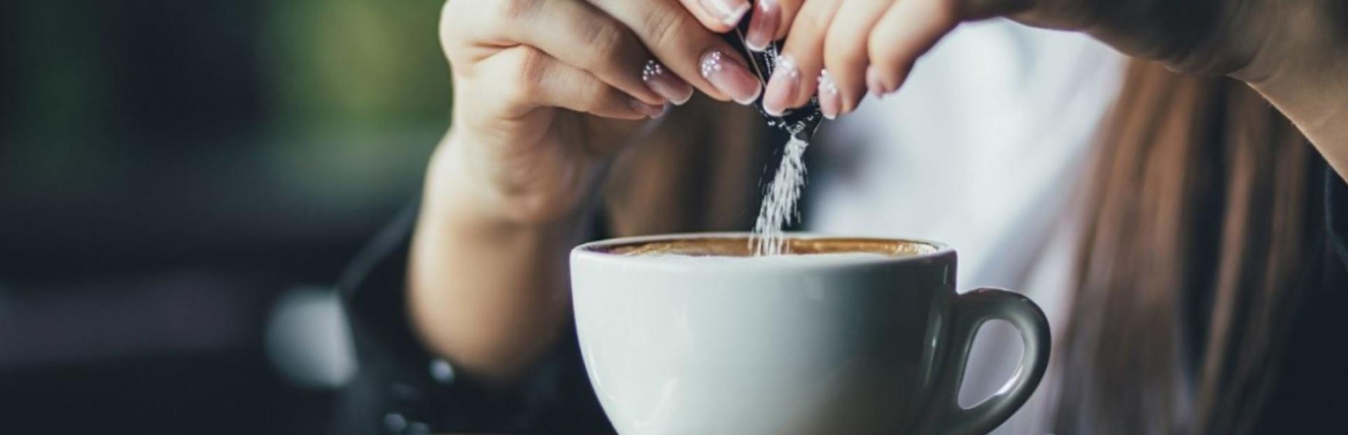 woman putting sugar in coffee
