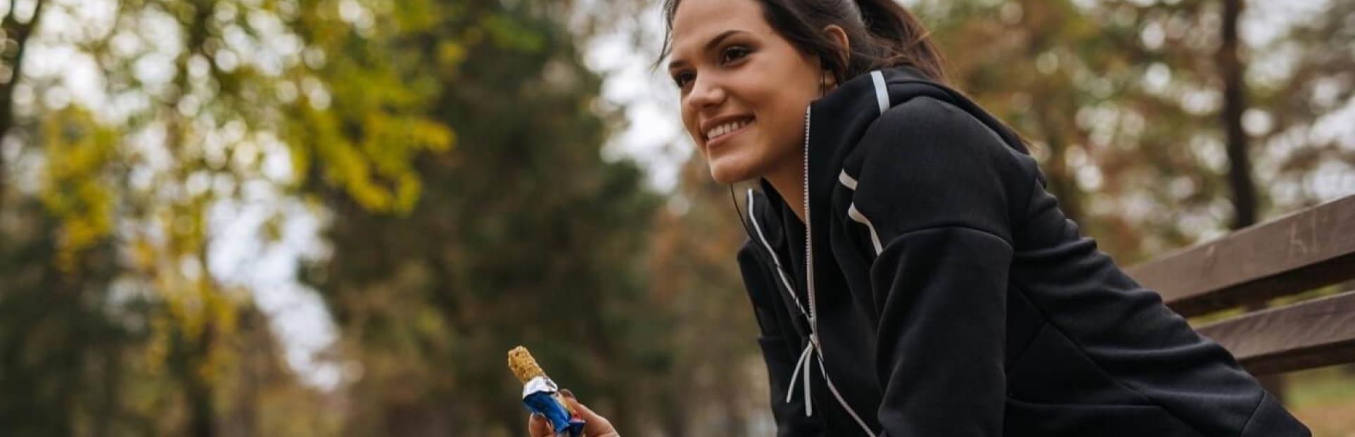 woman sitting on bench eating bar