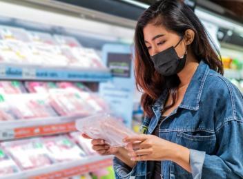 woman looking at meat in grocery store