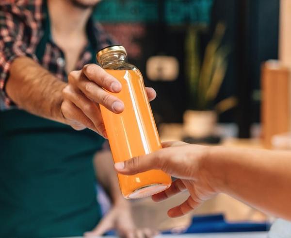 cashier handing customer bottle of juice