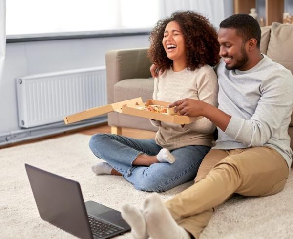 man and woman eating takeout pizza