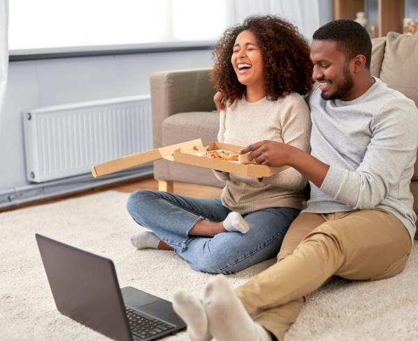 man and woman eating takeout pizza