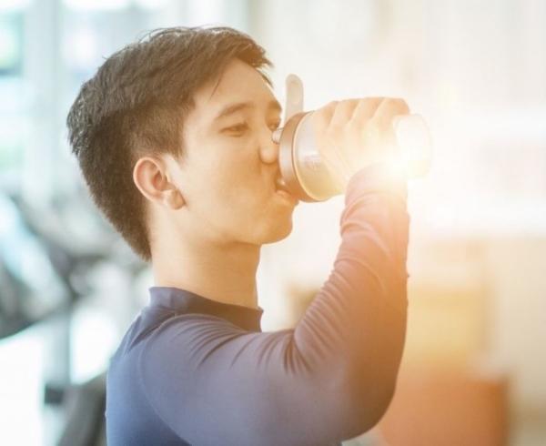 man with pre-workout beverage in gym gn