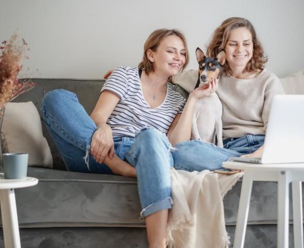 two girls and a dog sitting on couch