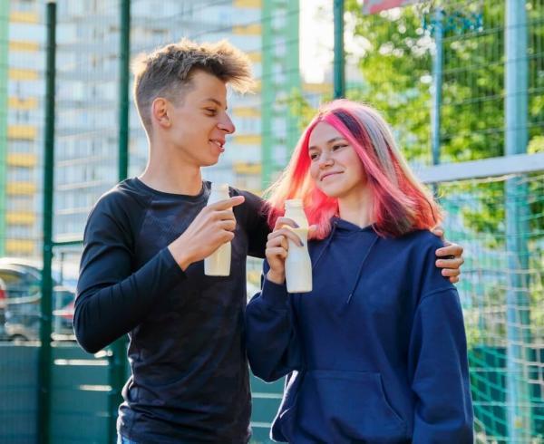 two teenagers walking and holding beverage