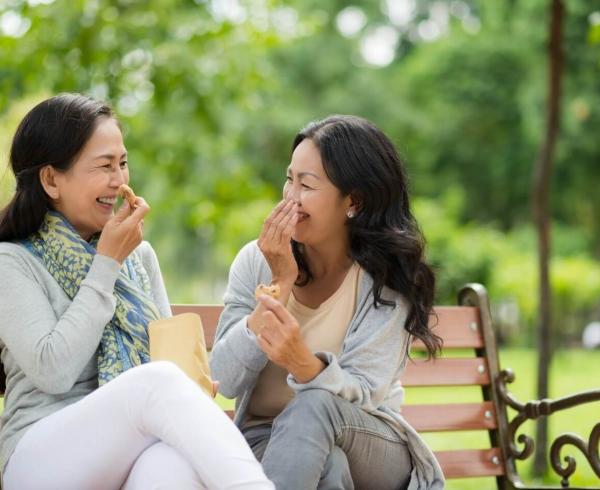 two women laughing on a bench