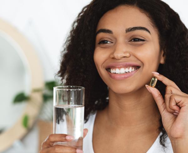 woman holding a supplement and water