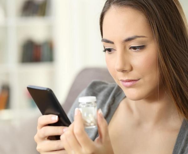 woman holding phone and supplements