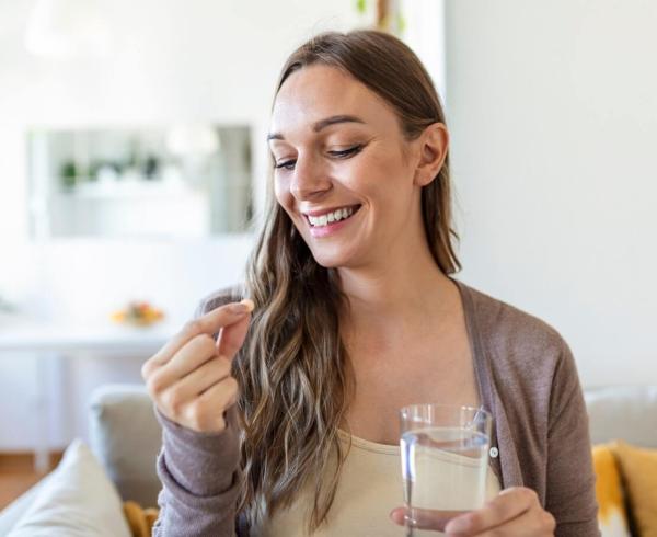 woman holding a supplement and water