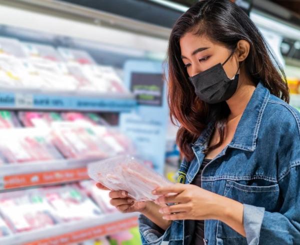 woman looking at meat in grocery store