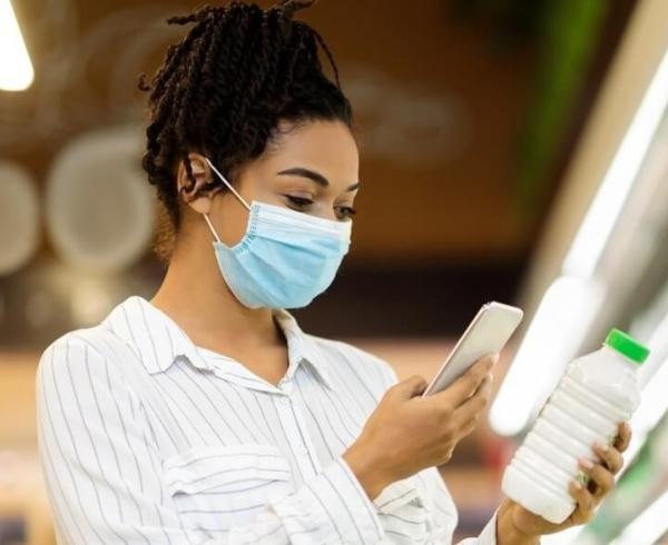 woman looking at phone and milk in store