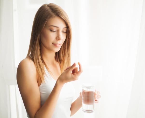 woman looking at pill with water