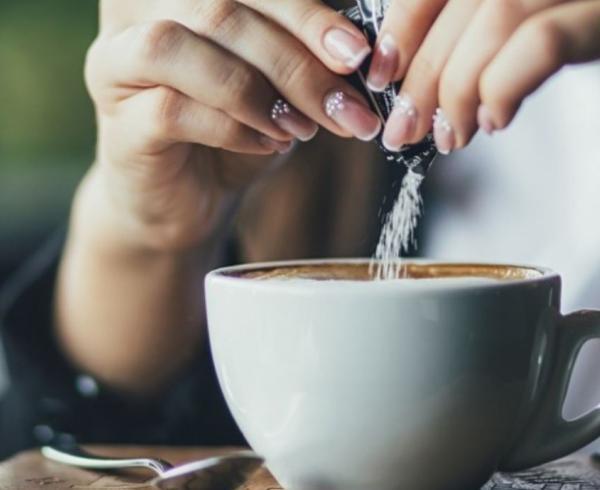 woman putting sugar in coffee