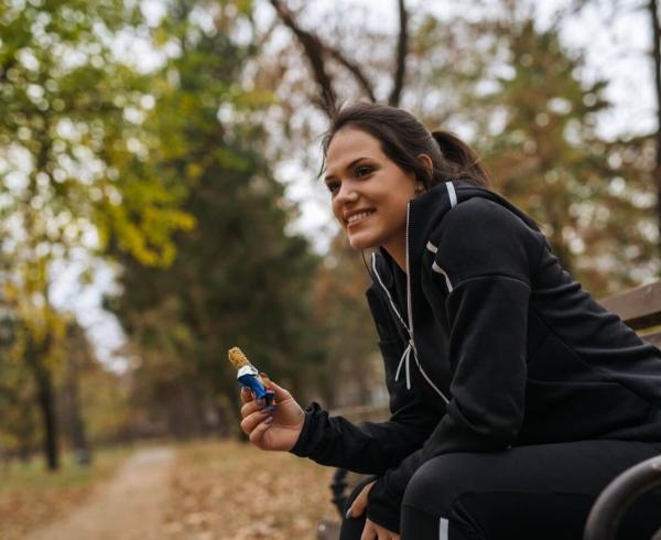 woman sitting on bench eating bar