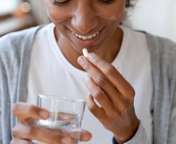 woman holding a supplement and water